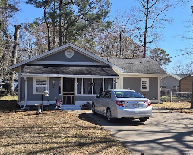 view of front of home with entry steps, roof with shingles, driveway, and a front yard