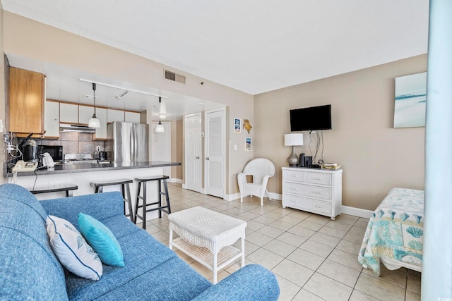 living area featuring light tile patterned flooring, visible vents, and baseboards