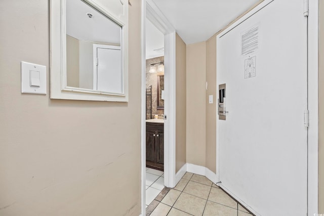 corridor with baseboards and light tile patterned floors