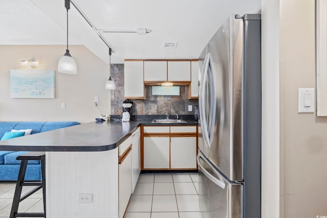 kitchen featuring a peninsula, white cabinets, hanging light fixtures, and freestanding refrigerator