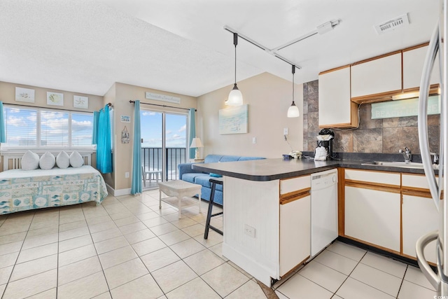 kitchen featuring white dishwasher, a peninsula, white cabinetry, open floor plan, and dark countertops