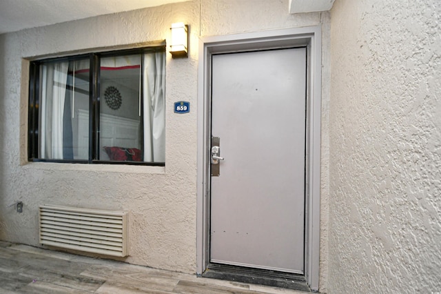 view of exterior entry featuring visible vents and stucco siding