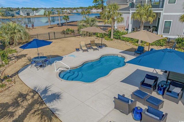 view of pool with a patio area, a water view, fence, and a fenced in pool