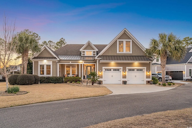 view of front facade featuring concrete driveway, metal roof, an attached garage, a standing seam roof, and a porch