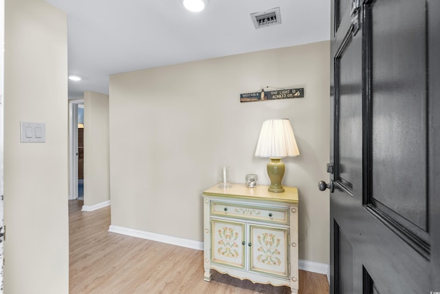 corridor with wood finished floors, visible vents, and baseboards