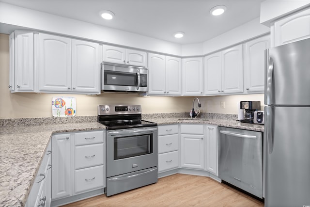 kitchen featuring light wood-style flooring, recessed lighting, a sink, white cabinetry, and appliances with stainless steel finishes