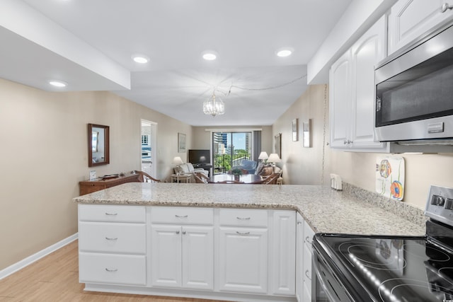 kitchen with an inviting chandelier, appliances with stainless steel finishes, open floor plan, light wood-type flooring, and a peninsula