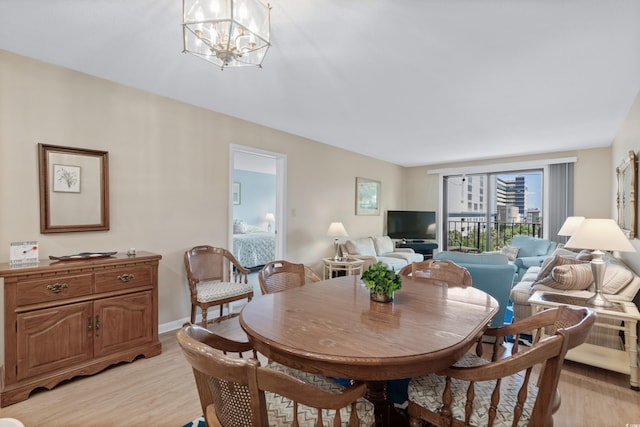 dining area with light wood-style floors, baseboards, and an inviting chandelier