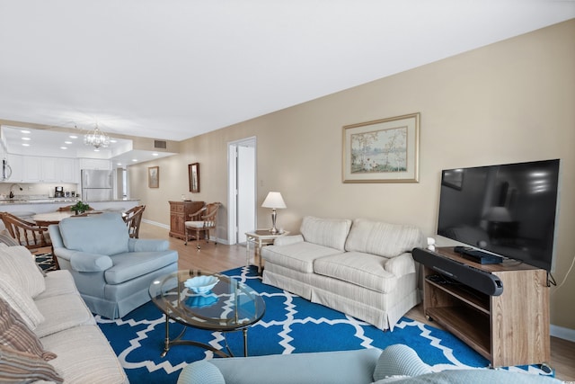 living area with visible vents, a notable chandelier, light wood-style flooring, and baseboards