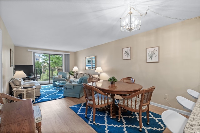 dining room with a notable chandelier, baseboards, and wood finished floors