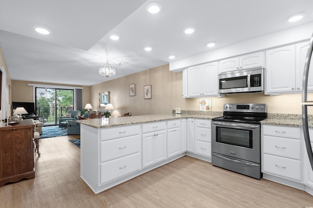 kitchen with light stone counters, a peninsula, white cabinetry, light wood-style floors, and appliances with stainless steel finishes