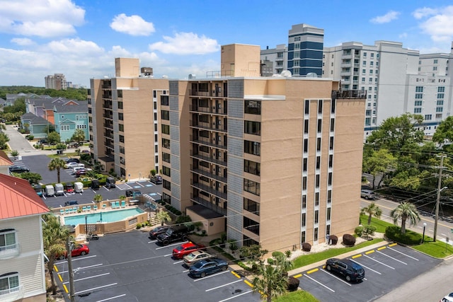 view of property with uncovered parking and a city view