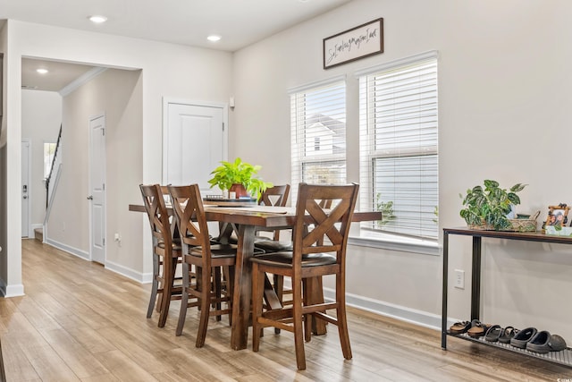 dining area with baseboards, light wood-type flooring, and a healthy amount of sunlight