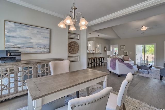 dining space featuring ceiling fan with notable chandelier, crown molding, and wood finished floors