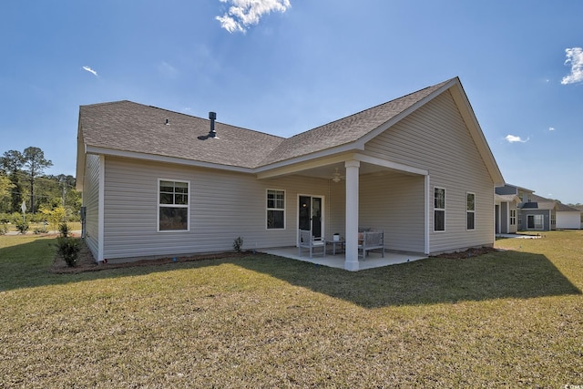 rear view of house featuring a patio area, a shingled roof, and a yard