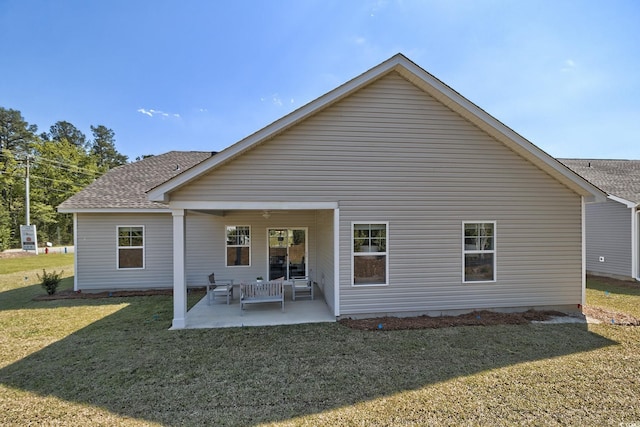 rear view of house featuring a lawn, a shingled roof, and a patio area