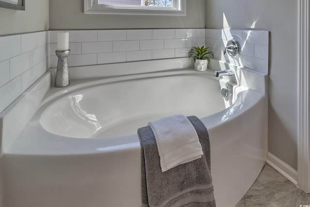 full bathroom featuring a garden tub and marble finish floor