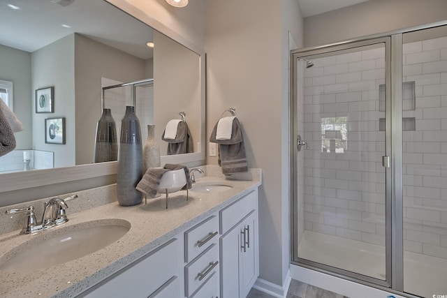 bathroom featuring double vanity, a stall shower, and a sink