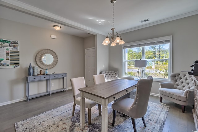 dining area with wood finished floors, baseboards, visible vents, an inviting chandelier, and crown molding