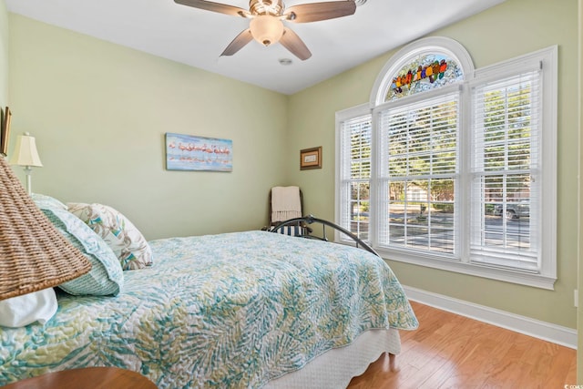 bedroom with ceiling fan, baseboards, and wood finished floors