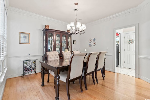 dining room with a notable chandelier, crown molding, baseboards, and light wood-style floors