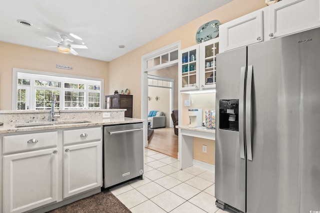 kitchen featuring ceiling fan, light tile patterned flooring, stainless steel appliances, a sink, and white cabinetry