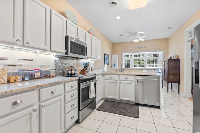 kitchen featuring light tile patterned flooring, stainless steel appliances, a peninsula, a sink, and visible vents