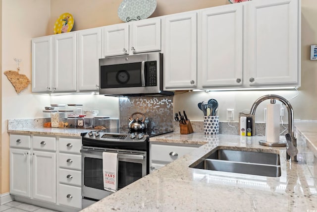 kitchen with white cabinetry, appliances with stainless steel finishes, light stone counters, and a sink