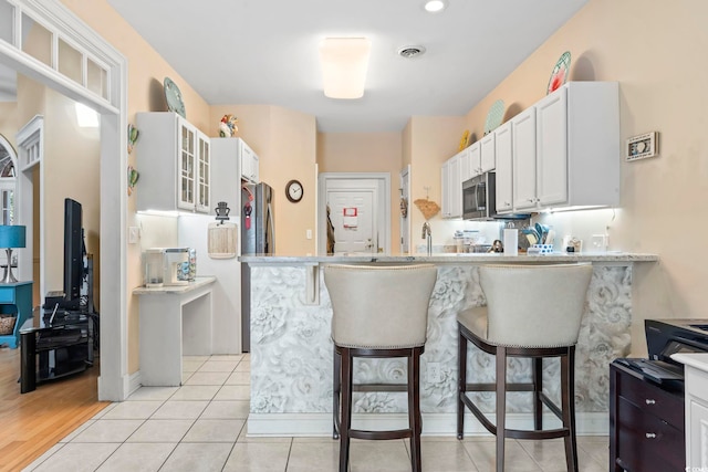 kitchen featuring light tile patterned floors, white cabinetry, a breakfast bar area, and stainless steel appliances