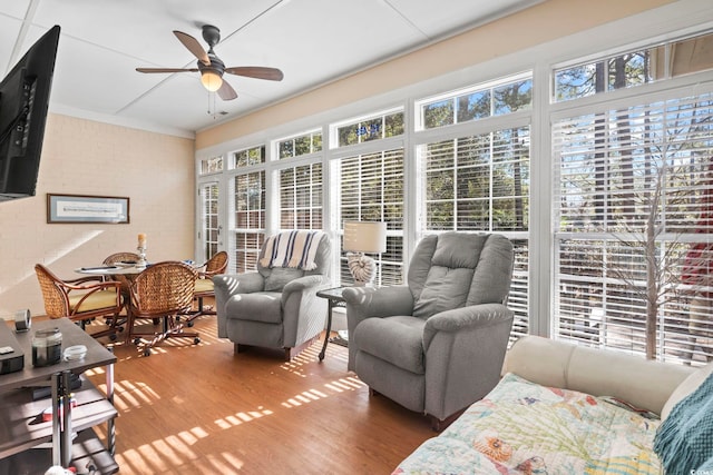 interior space with ceiling fan, brick wall, and wood finished floors