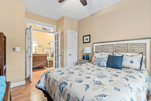 bedroom featuring a ceiling fan, baseboards, wood finished floors, and french doors