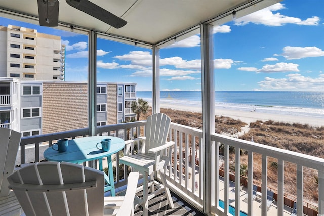 balcony with a water view, ceiling fan, and a beach view