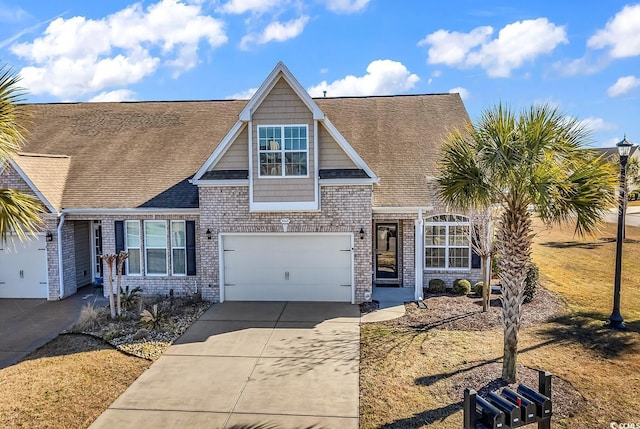 view of front facade with an attached garage, a shingled roof, concrete driveway, and brick siding