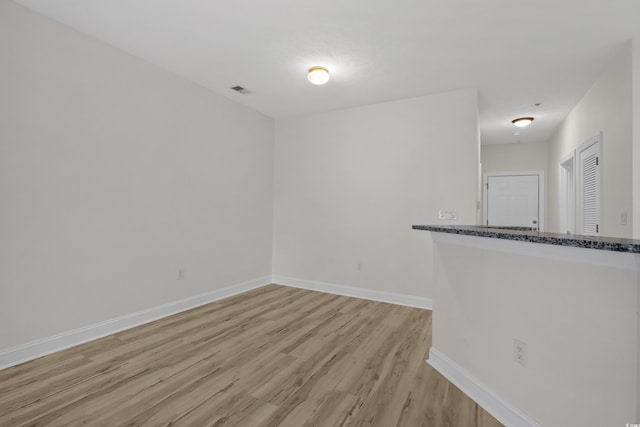 spare room with light wood-type flooring, visible vents, and baseboards