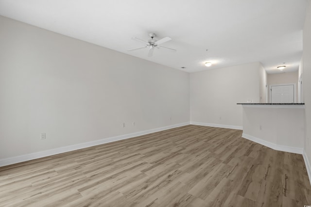 unfurnished room with ceiling fan, light wood-type flooring, and baseboards