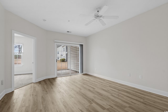 spare room featuring baseboards, a ceiling fan, visible vents, and light wood-style floors