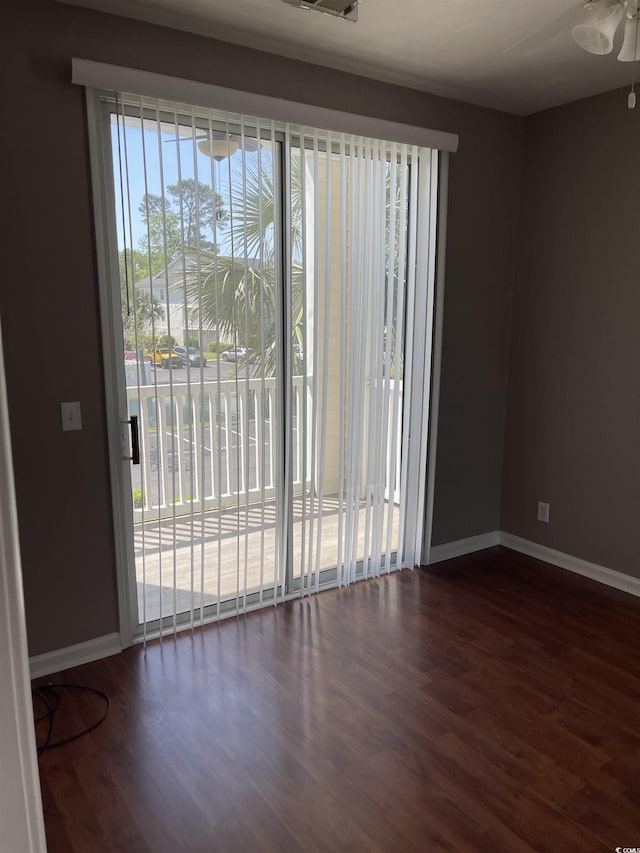 spare room featuring ceiling fan, baseboards, and dark wood-style flooring