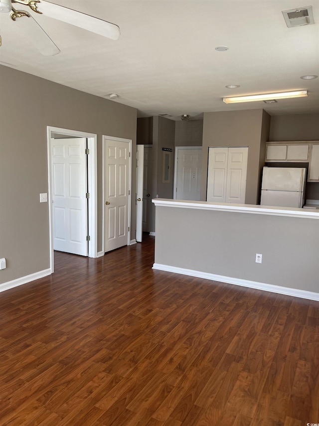 empty room featuring baseboards, visible vents, and dark wood-style flooring