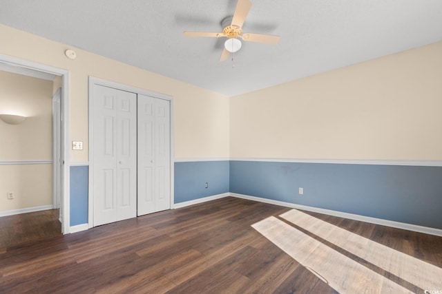 unfurnished bedroom with dark wood-type flooring, a closet, ceiling fan, and baseboards