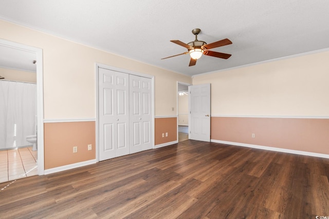 unfurnished bedroom with dark wood-type flooring, connected bathroom, and baseboards