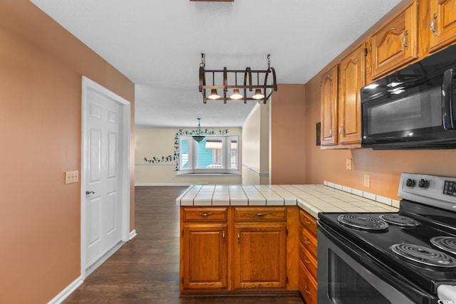 kitchen featuring a peninsula, stainless steel electric range, black microwave, and brown cabinets