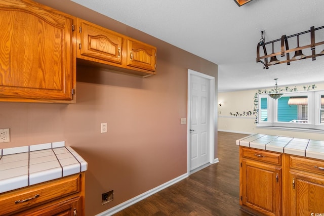 kitchen with brown cabinets, tile countertops, and baseboards