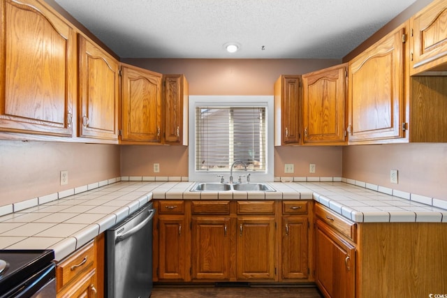 kitchen with stainless steel dishwasher, brown cabinetry, a sink, and tile counters