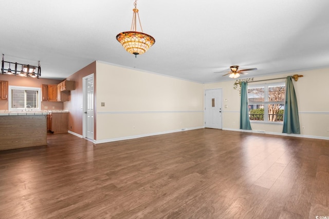 unfurnished living room with dark wood-type flooring, a sink, a ceiling fan, and baseboards