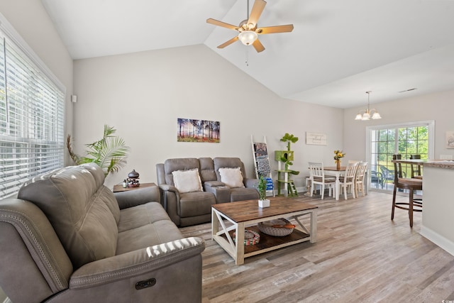 living area featuring a chandelier, a ceiling fan, light wood-style flooring, and high vaulted ceiling