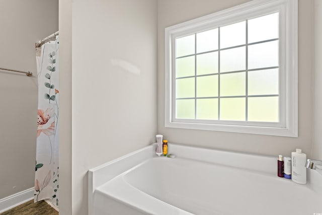 full bath featuring a garden tub and a shower with shower curtain