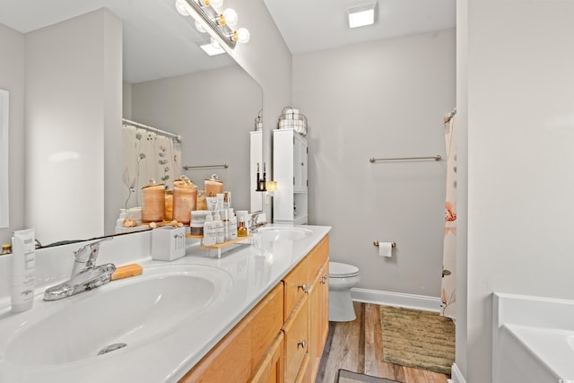 full bath featuring wood finished floors, toilet, baseboards, double vanity, and a bathtub