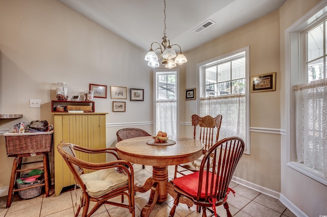 dining room featuring light tile patterned floors, baseboards, visible vents, lofted ceiling, and a chandelier