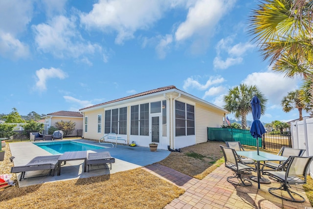 view of swimming pool with a patio area, a fenced in pool, a fenced backyard, and a sunroom