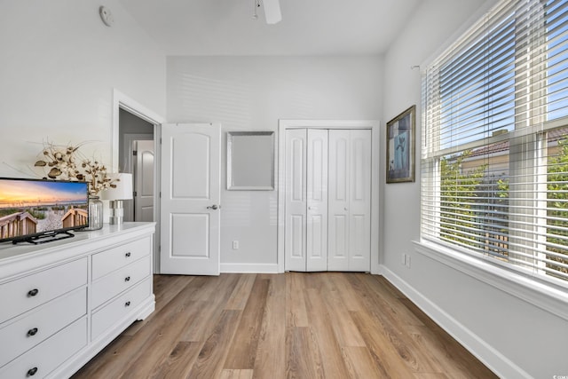 unfurnished bedroom with a closet, multiple windows, baseboards, and light wood-style floors